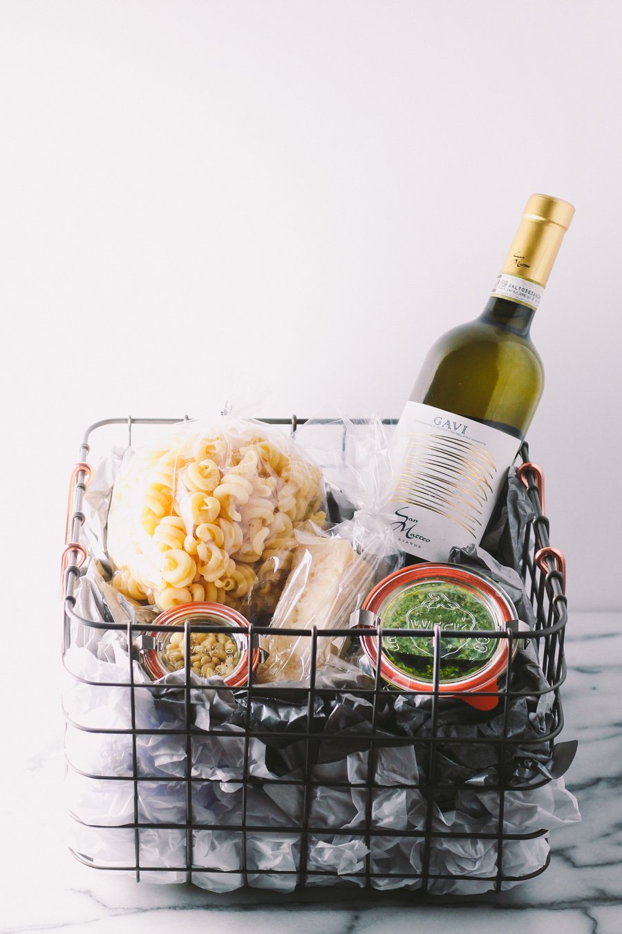 treat the italophile in your life with a homemade italian gift basket this holiday season. a beautiful basket with italian wine, good cheese & pasta, & homemade kale pesto makes perfect secret santa gift, hostess gift, or christmas gift for any italian-lover in your life! | a plays well with butter holiday gift basket series