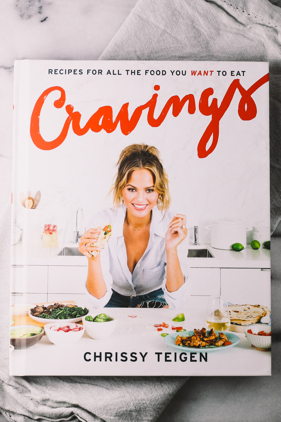 homemade holiday kitchenista gift basket essential #1: chrissy teigen's cookbook | a homemade gift basket perfect for the young & trendy person who is just starting to take interest in food & dining. this gift basket also features some prosecco for a festive holiday cocktail, on-trend bar gadgets.