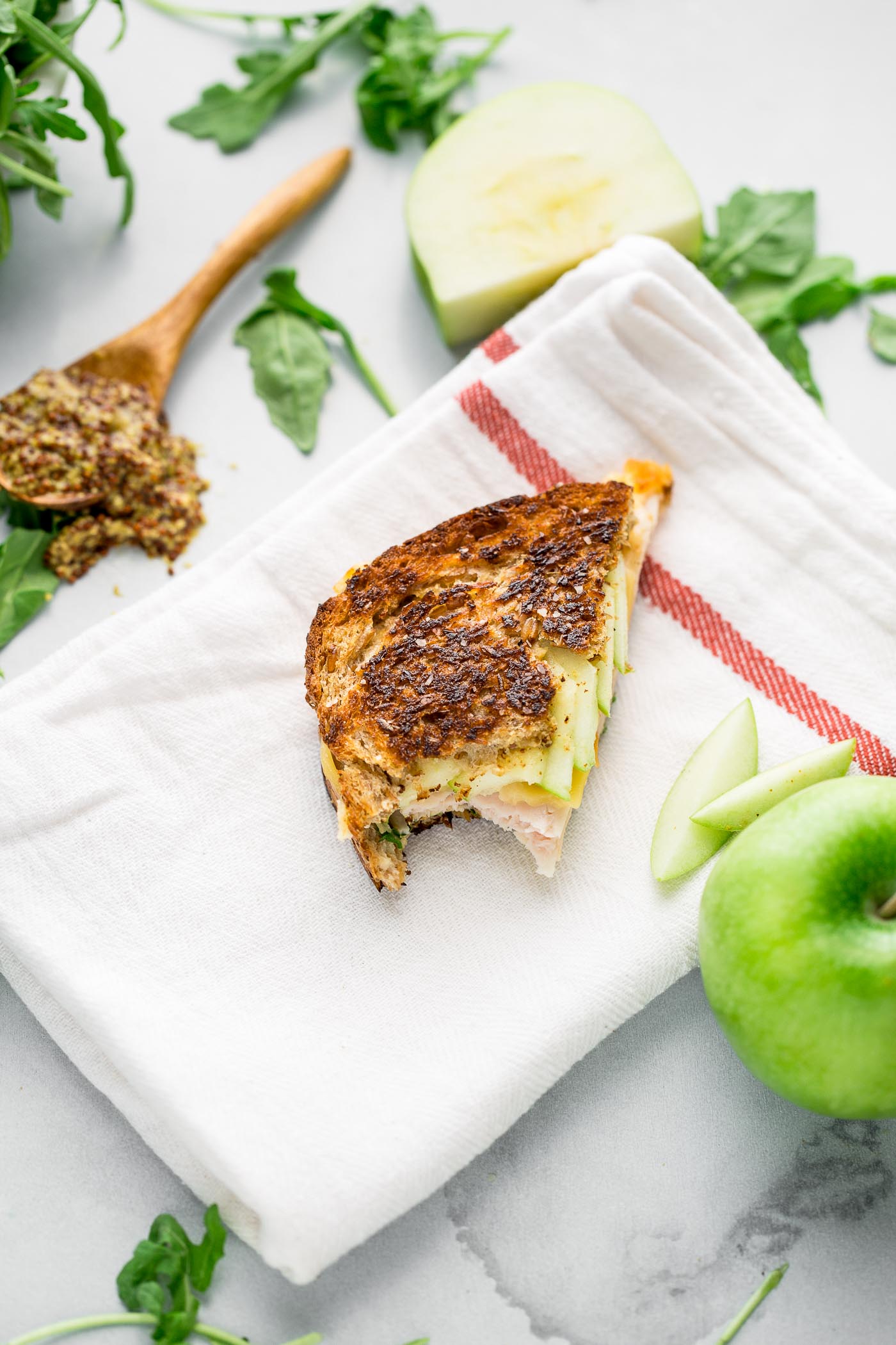 autumn grilled cheese sandwiches stuffed with fall flavor! hearty whole-grain bread slathered in whole grain mustard & sandwiched around melty gouda, smoked turkey, & crisp granny smith apples. the only thing missing is a big dunk into a bowl of tomato soup! #playswellwithbutter #comfortfood #grilledcheese #grannysmith