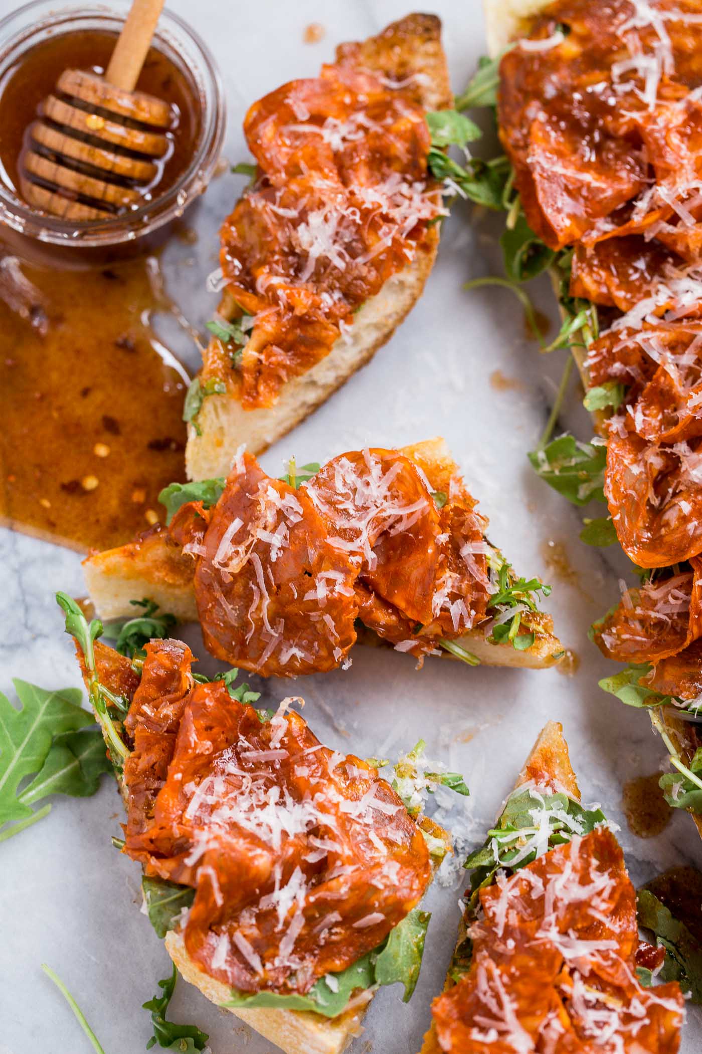 easy chorizo french breads with manchego, fig spread, & harissa, & covered in big fat drizzles of homemade spicy paprika honey. an easy & elegant appetizer! an easy & elegant appetizer or snack, perfect for holiday entertaining! #playswellwithbutter #chorizo #harissa #manchego #holidayparty #cocktailparty #appetizer