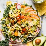 a healthy kale taco salad with chipotle lime chicken, roasted jalapeno vinaigrette, black beans, corn, pepper jack cheese, and a quick pico de gallo. this lightened-up take on a taco salad will be your new favorite! #playswellwithbutter #healthyrecipe #mealprep #healthyrecipe #kale #tacosalad #saladrecipe