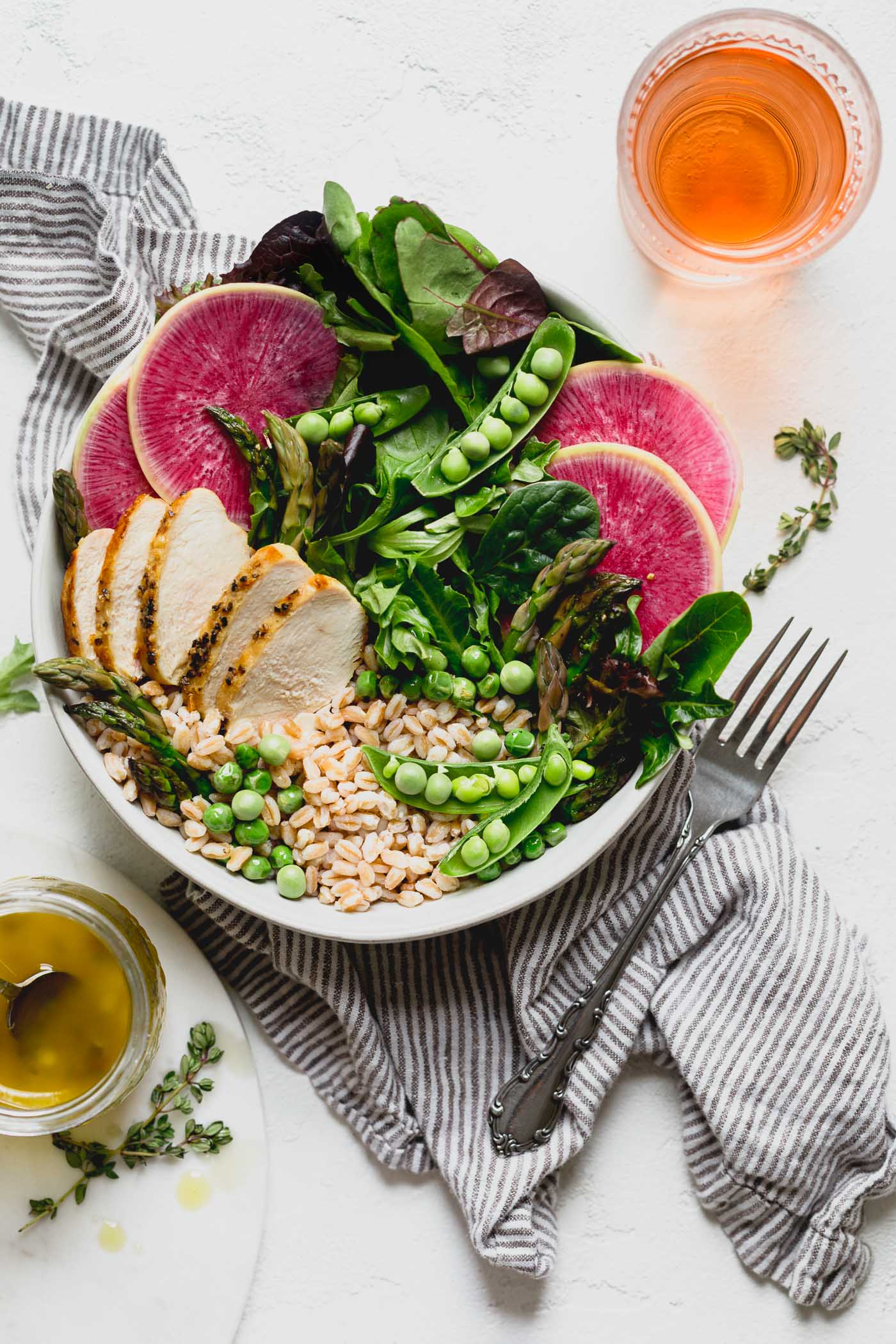 a healthy & seasonal springtime grain bowl with farro, asparagus, spring peas, greens, herbed chicken & a simple homemade lemon vinaigrette. this spring goddess grain bowl recipe is totally wholesome, meal prep friendly, & comes together in 30 minutes or less. the perfect easy weeknight dinner for this spring! #grainbowl #healthygrainbowl #saladrecipe #mealpreprecipe #springrecipe #asparagus #springpeas