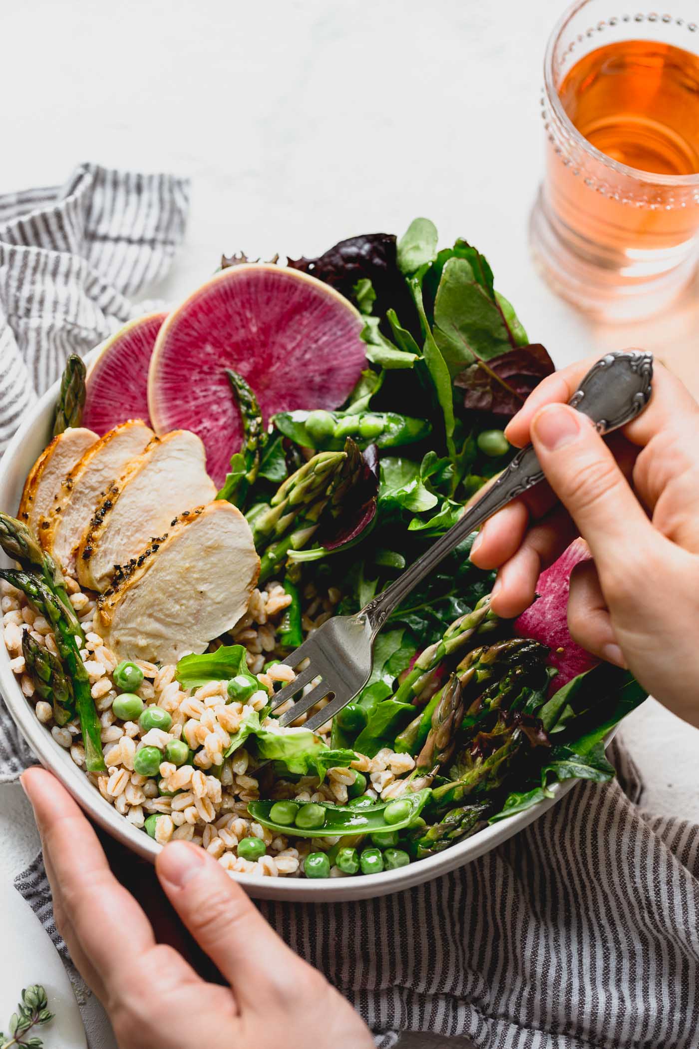 a healthy & seasonal springtime grain bowl with farro, asparagus, spring peas, greens, herbed chicken & a simple homemade lemon vinaigrette. this spring goddess grain bowl recipe is totally wholesome, meal prep friendly, & comes together in 30 minutes or less. the perfect easy weeknight dinner for this spring! #grainbowl #healthygrainbowl #saladrecipe #mealpreprecipe #springrecipe #asparagus #springpeas