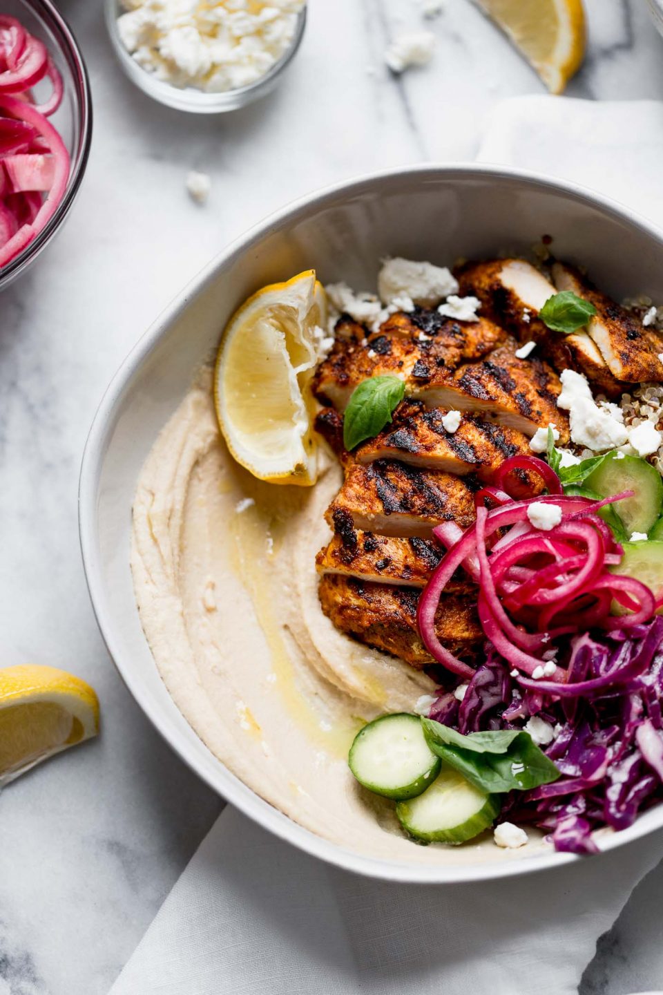 healthy & hearty grilled chicken shawarma hummus bowls!!! a generous dollop of hummus gets served with quinoa, a light red cabbage slaw, feta, & grilled chicken shawarma. a healthy & easy weeknight dinner, or an easy meal to prep for grab-&-go lunches this week! #playswellwtihbutter #hummusbowls #chickenshawarma #chickenshawarma #healthyrecipe #easyrecipe #mealprep #bowlrecipe