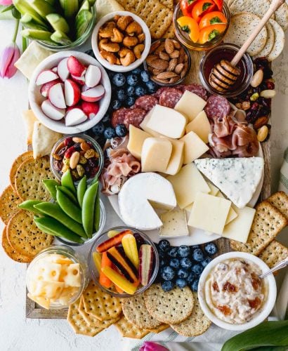 building a stunning & delicious ultimate cheese board on a budget couldn’t be easier when you take advantage of the low prices at aldi! this ultimate aldi cheese board is inspired by springtime with a variety of cheeses, crackers, veggies, & nuts, & is perfect for any spring celebration - mother’s day, father’s day, graduation parties, bridal showers, or spring brunches! #playswellwithbutter #cheeseboard #howtomakeacheeseboard #easycheeseboard #cheeseboardideas #springcheeseboard #bridalshoweridea #appetizeridea #appetizerrecipe #aldirecipe #whattobuyataldi #aldifinds