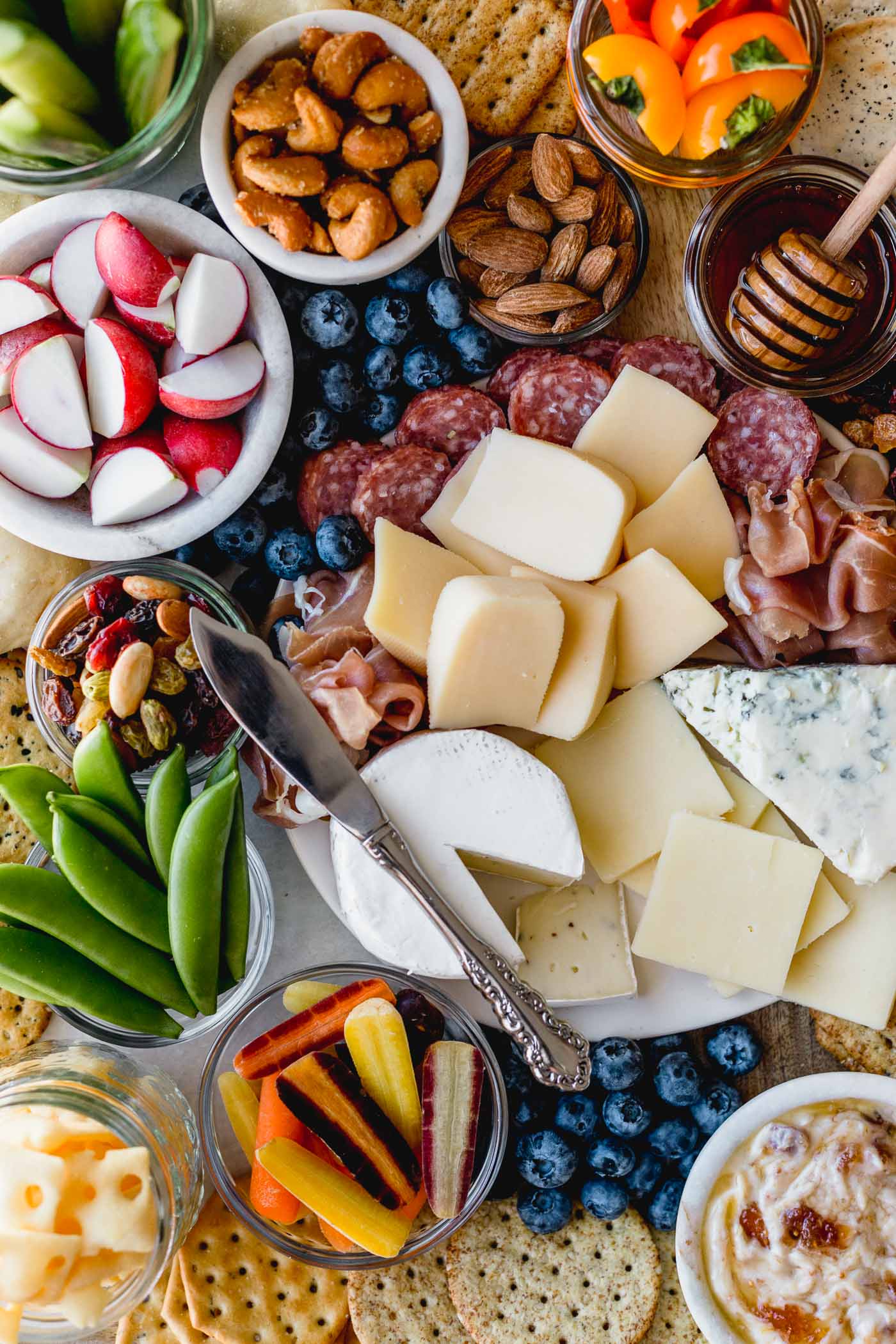 building a stunning & delicious ultimate cheese board on a budget couldn’t be easier when you take advantage of the low prices at aldi! this ultimate aldi cheese board is inspired by springtime with a variety of cheeses, crackers, veggies, & nuts, & is perfect for any spring celebration - mother’s day, father’s day, graduation parties, bridal showers, or spring brunches! #playswellwithbutter #cheeseboard #howtomakeacheeseboard #easycheeseboard #cheeseboardideas #springcheeseboard #bridalshoweridea #appetizeridea #appetizerrecipe #aldirecipe #whattobuyataldi #aldifinds