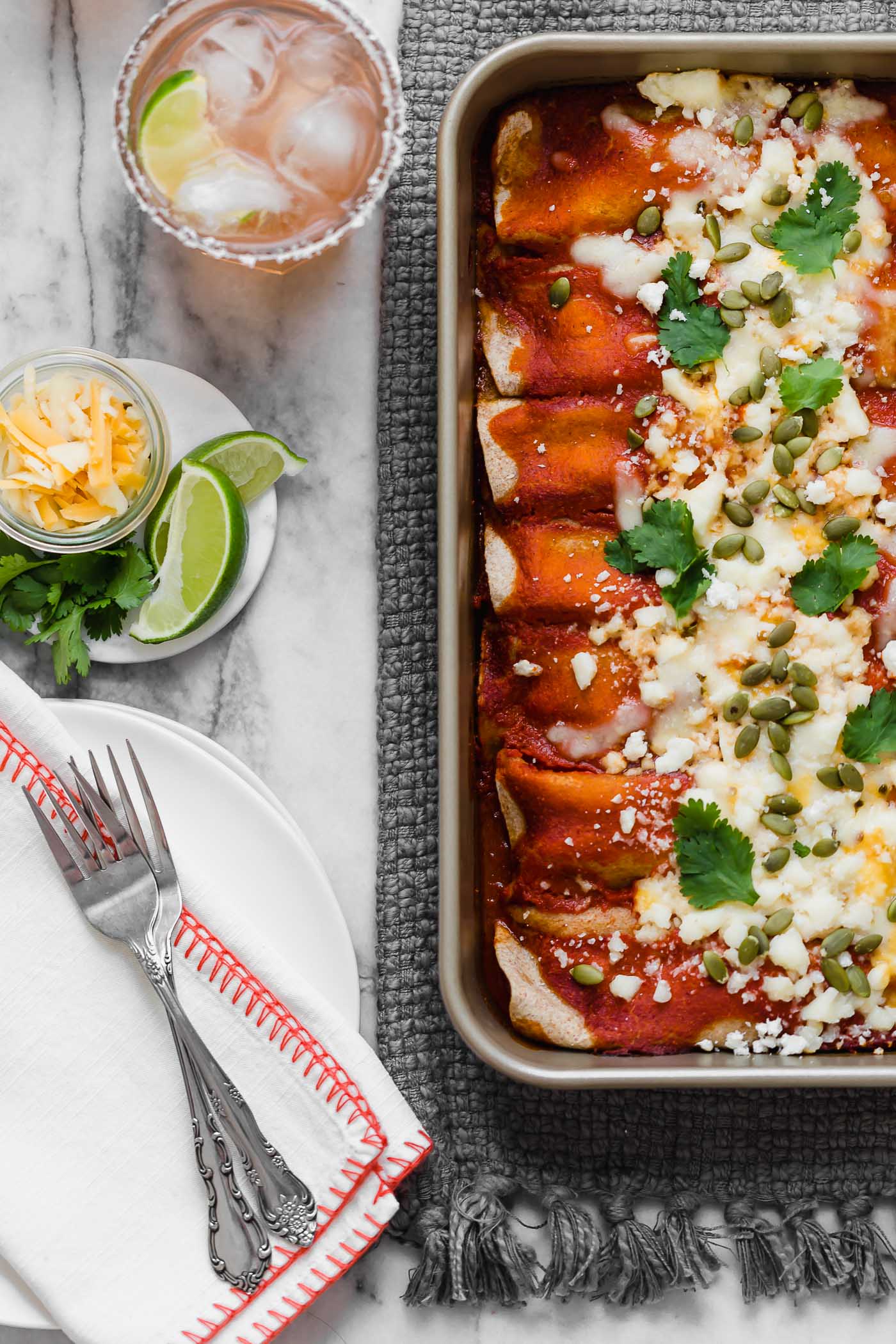 an easy & healthy chicken enchilada recipe perfect for weeknight cooking! these weeknight chicken enchiladas have a filling of pulled chicken, bell pepper sweet onion, black beans, & cheese, and get covered in the easiest blender enchilada sauce made from ancho chiles. the only thing missing is a couple of margaritas! #playswellwithbutter #easychickenenchiladas #healthyenchiladas #mexicanfoodrecipes #homemadenchiladasauce #enchiladasaucerecipe