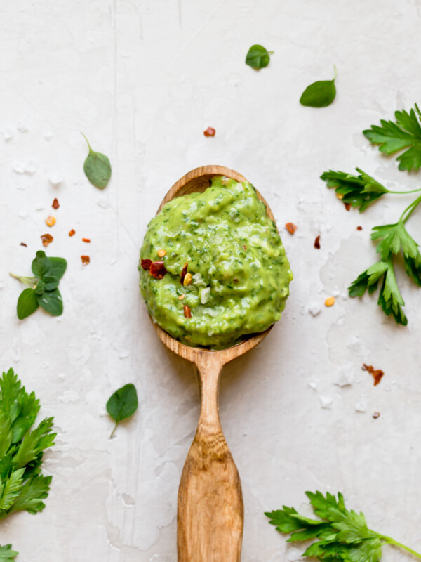 traditional chimichurri gets a fun twist with this easy 10-minute avocado chimichurri sauce recipe! made with tons of fresh herbs (cilantro, parsley, oregano), plenty of red wine vinegar, & avocado, this avocado chimichurri is tangy, flavorful, & SO creamy. perfect to top any grilled meats this summer, to spread on a sandwich, to serve as a dip, or to eat by the spoonful! vegan & whole30 compliant! #playswellwithbutter #avocadochimichurri #chimichurrisauce #veganrecipe #easyrecipe