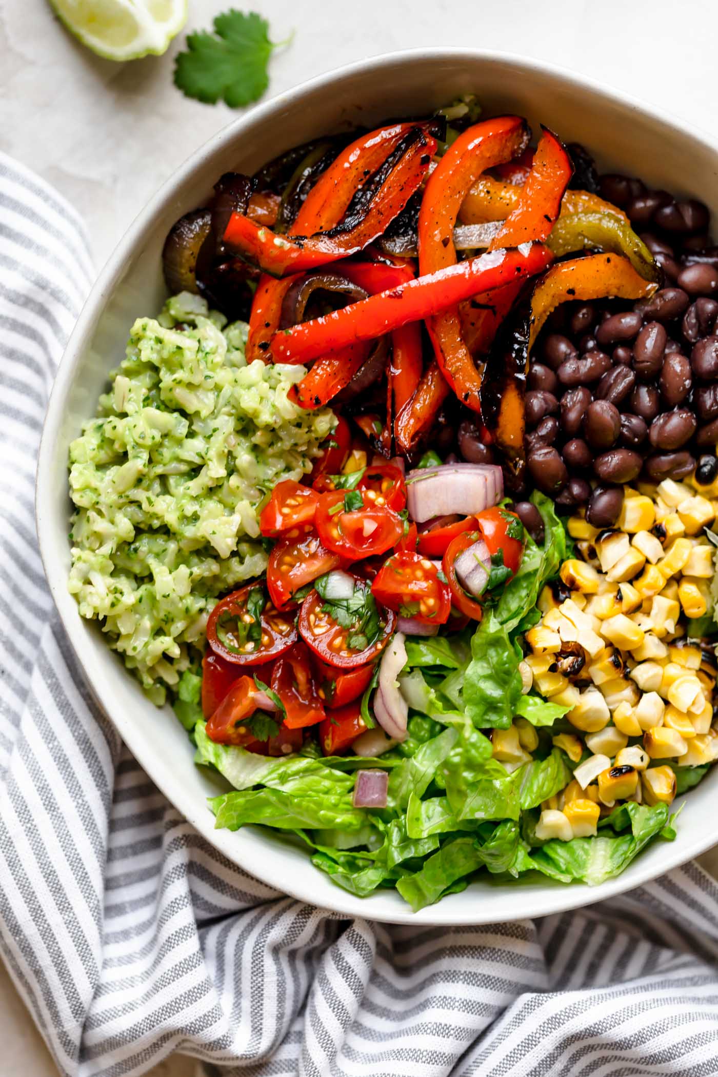 these easy & healthy grilled veggie burrito bowls are loaded with flavor! grilled peppers, onions, & sweet corn get paired with black beans & served with green rice - brown rice that’s tossed in a creamy avocado sauce. move over chipotle! wholesome, plant-based, naturally vegan & gluten-free, & meal prep-friendly! & #playswellwithbutter #veggieburritobowl #healthyburritobowlrecipe #easyrecipe #healthyrecipe #mealpreprecipe #grilledvegetables #greenrice #vegetarian #plantbased #vegan #easyvegandinnerrecipe #glutenfree #easyglutenfreereceipe