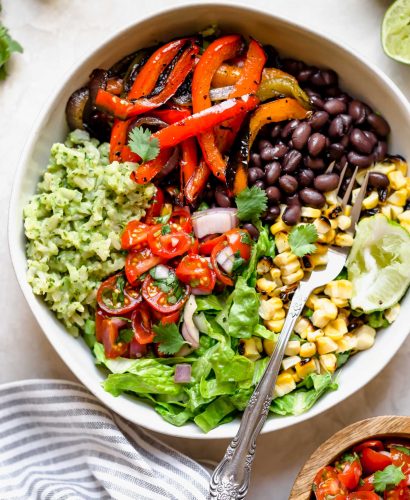 these easy & healthy grilled veggie burrito bowls are loaded with flavor! grilled peppers, onions, & sweet corn get paired with black beans & served with green rice - brown rice that’s tossed in a creamy avocado sauce. move over chipotle! wholesome, plant-based, naturally vegan & gluten-free, & meal prep-friendly! & #playswellwithbutter #veggieburritobowl #healthyburritobowlrecipe #easyrecipe #healthyrecipe #mealpreprecipe #grilledvegetables #greenrice #vegetarian #plantbased #vegan #easyvegandinnerrecipe #glutenfree #easyglutenfreereceipe