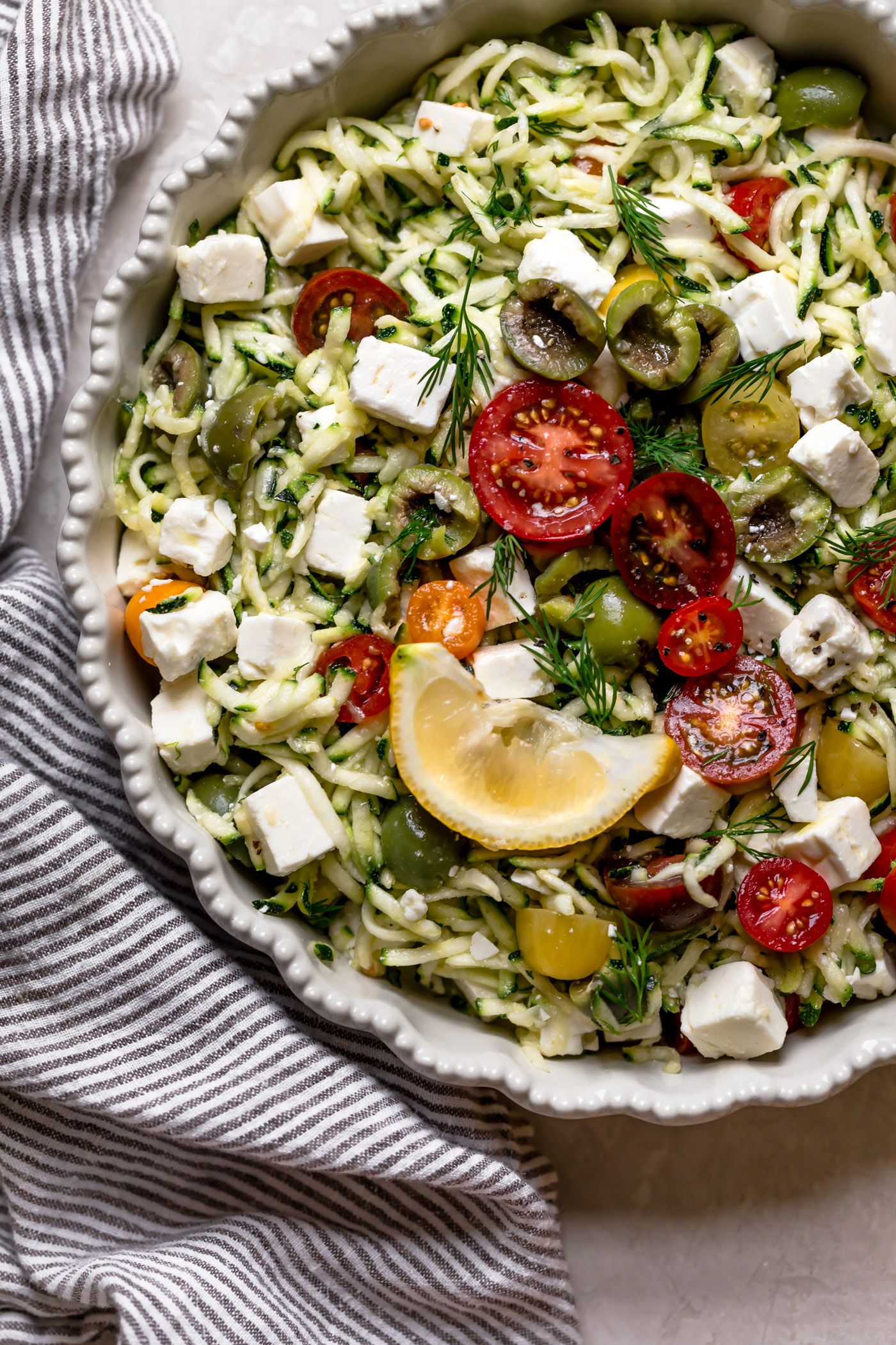 a fresh, fast, & light summertime grated zucchini salad! this easy salad has simple summer ingredients like shredded zucchini, tomatoes, castelvetrano olives, & tangy feta cheese. great for an easy weeknight dinner or side dish, or perfect for feeding a crowd at summer parties & BBQs! vegetarian, naturally gluten-free, low-carb, raw, totally healthy & fresh! #playswellwithbutter #zucchinisalad #gratedzucchini #zucchinirecipe #shreddedzucchini #summersalad #sidedish #rawsalad #lowcarbrecipe
