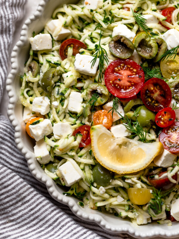 bowl of grated zucchini salad with lemon wedge