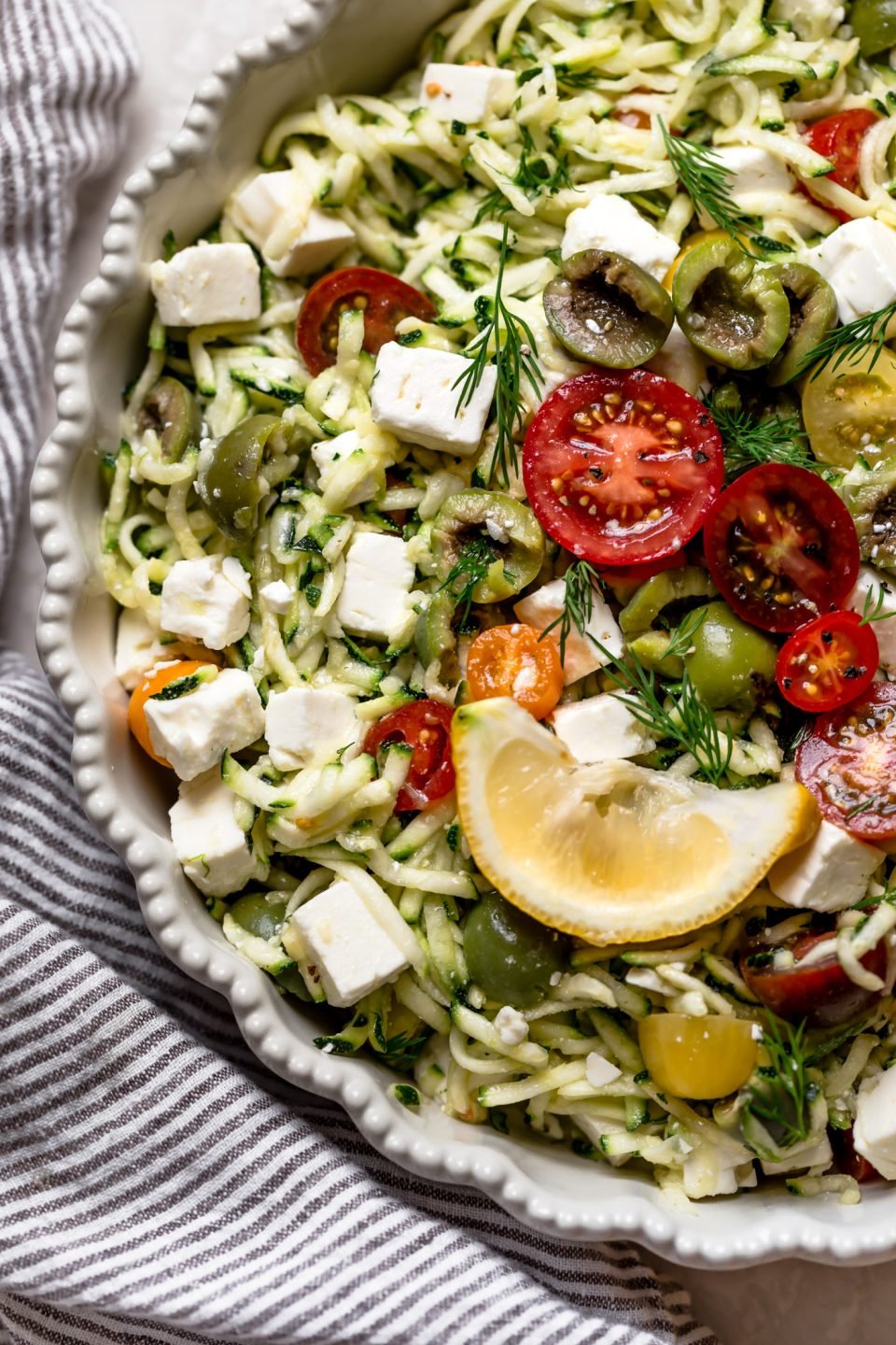 bowl of grated zucchini salad with lemon wedge