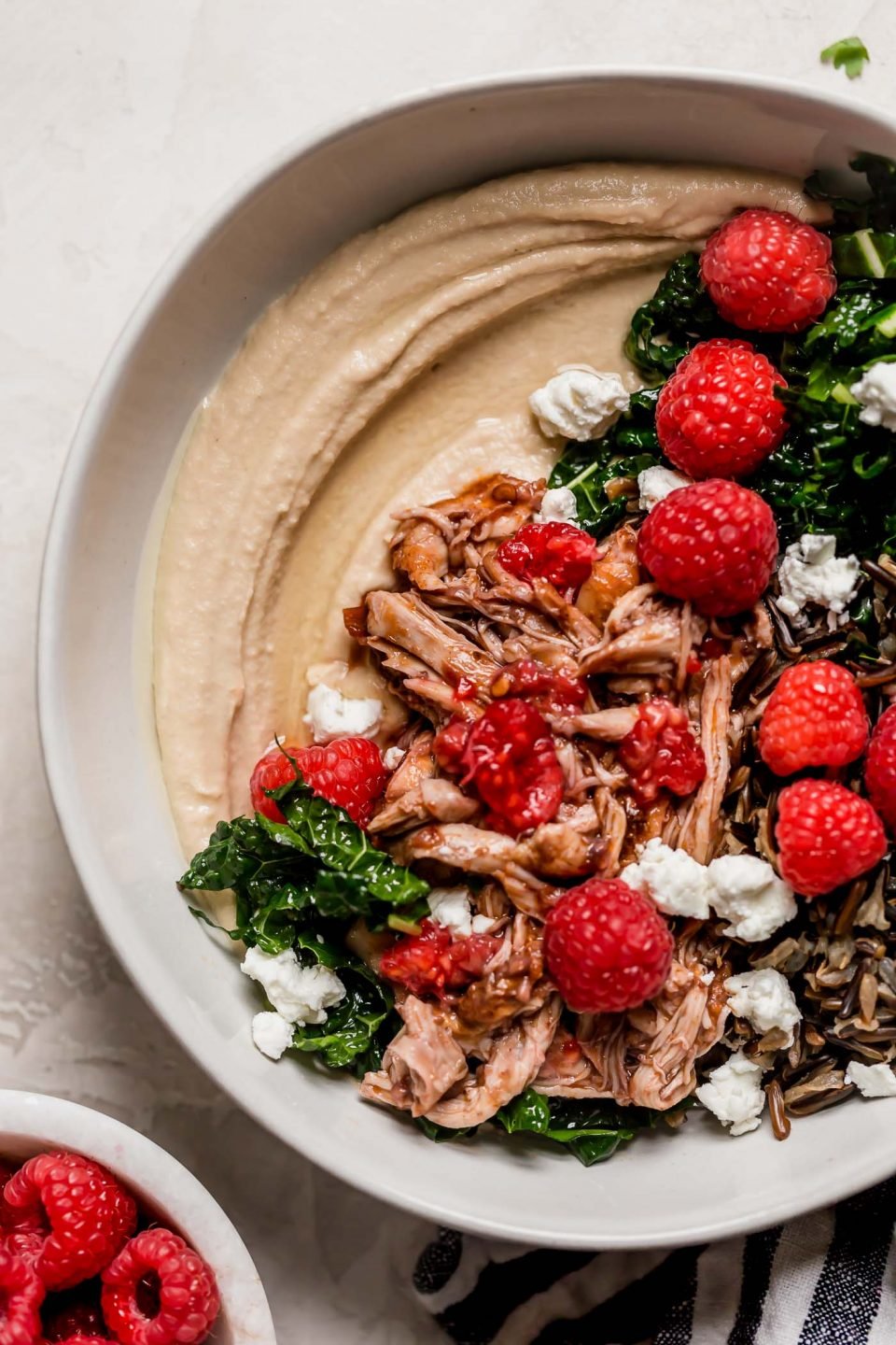 an easy one-skillet recipe for chipotle raspberry chicken, served overtop an autumn hummus bowl with creamy, garlicky hummus, finely shredded kale, wild rice, goat cheese, & some extra raspberries. chipotle raspberry chicken autumn hummus bowls are the perfect healthy & easy weeknight dinner, or an easy meal to prep for grab-&-go lunches this week! #hummusbowl #chipotleraspberrychicken #raspberryrecipes #raspberrydinnerrecipes #healthyrecipe #skilletrecipe #bowlrecipe #easyrecipe #mealprep