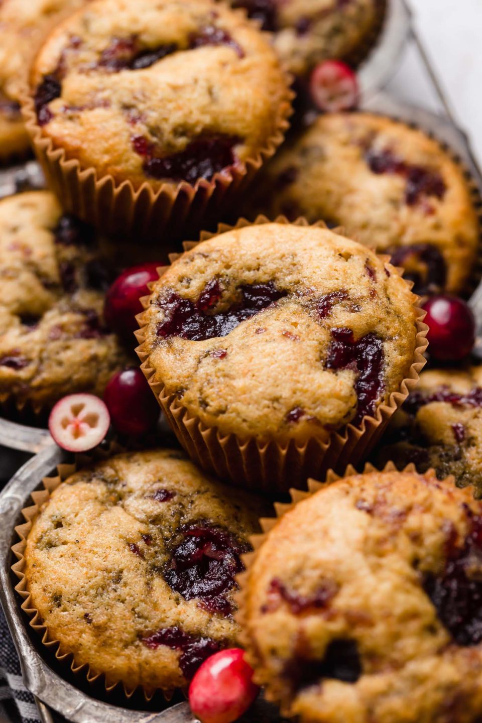 Side angle of cranberry cornbread muffins stacked on top of a vintage muffin pan.