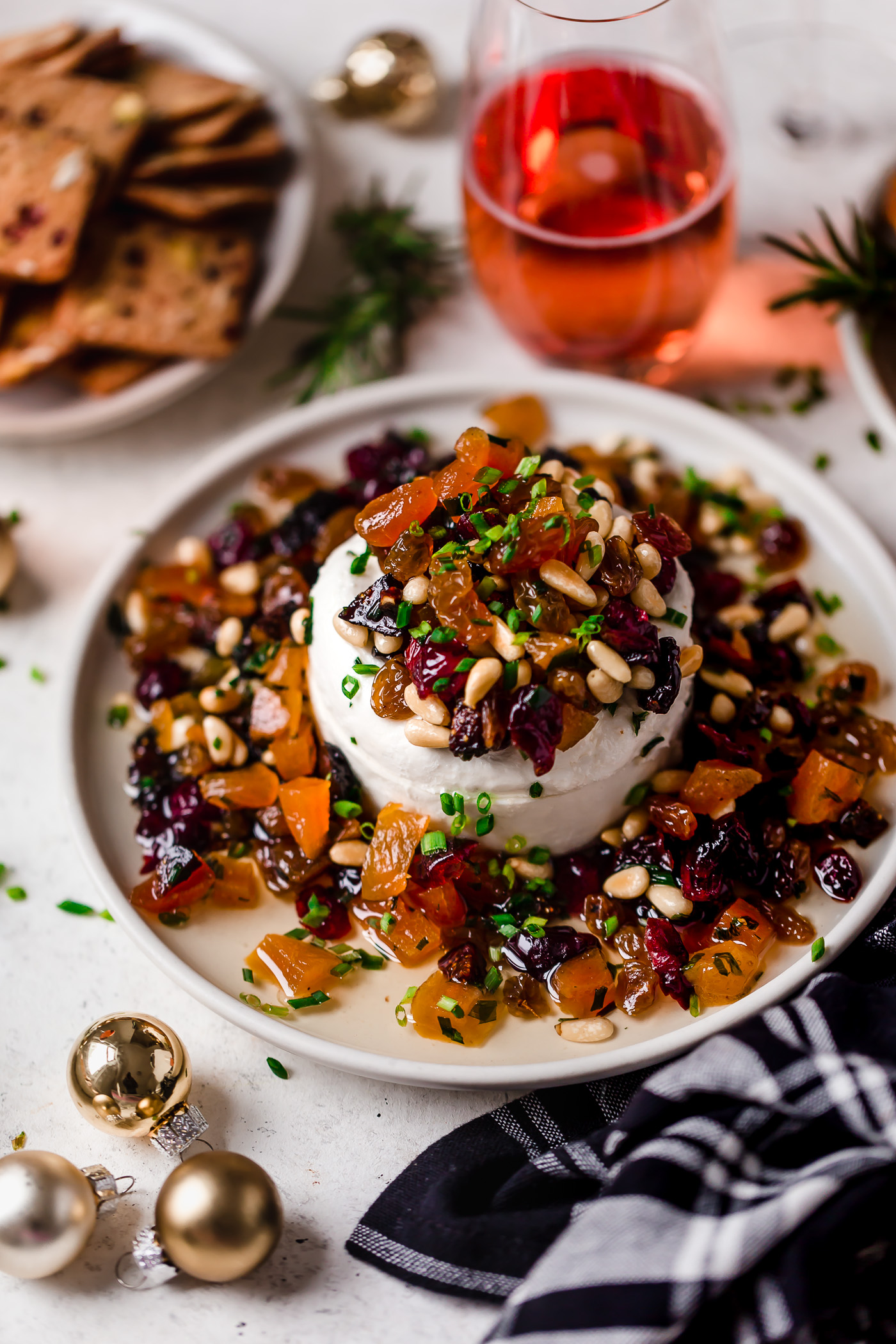 bejeweled holiday marinated goat cheese. easy & beautiful appetizer for any holiday party, this bejeweled holiday marinated goat cheese is always a total show stopper. dried fruits (apricots, golden raisins, figs, cranberries) marinated with fresh herbs & pine nuts, then served over a generous portion of goat cheese. this marinated goat cheese recipe only takes 10 minutes to prep & is always a hit! #playswellwithbutter #marinatedgoatcheese #cheeseball #holidayappetizers #crowdpleaserappetizer