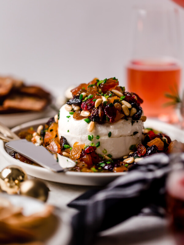 bejeweled holiday marinated goat cheese. easy & beautiful appetizer for any holiday party, this bejeweled holiday marinated goat cheese is always a total show stopper. dried fruits (apricots, golden raisins, figs, cranberries) marinated with fresh herbs & pine nuts, then served over a generous portion of goat cheese. this marinated goat cheese recipe only takes 10 minutes to prep & is always a hit! #playswellwithbutter #marinatedgoatcheese #cheeseball #holidayappetizers #crowdpleaserappetizer