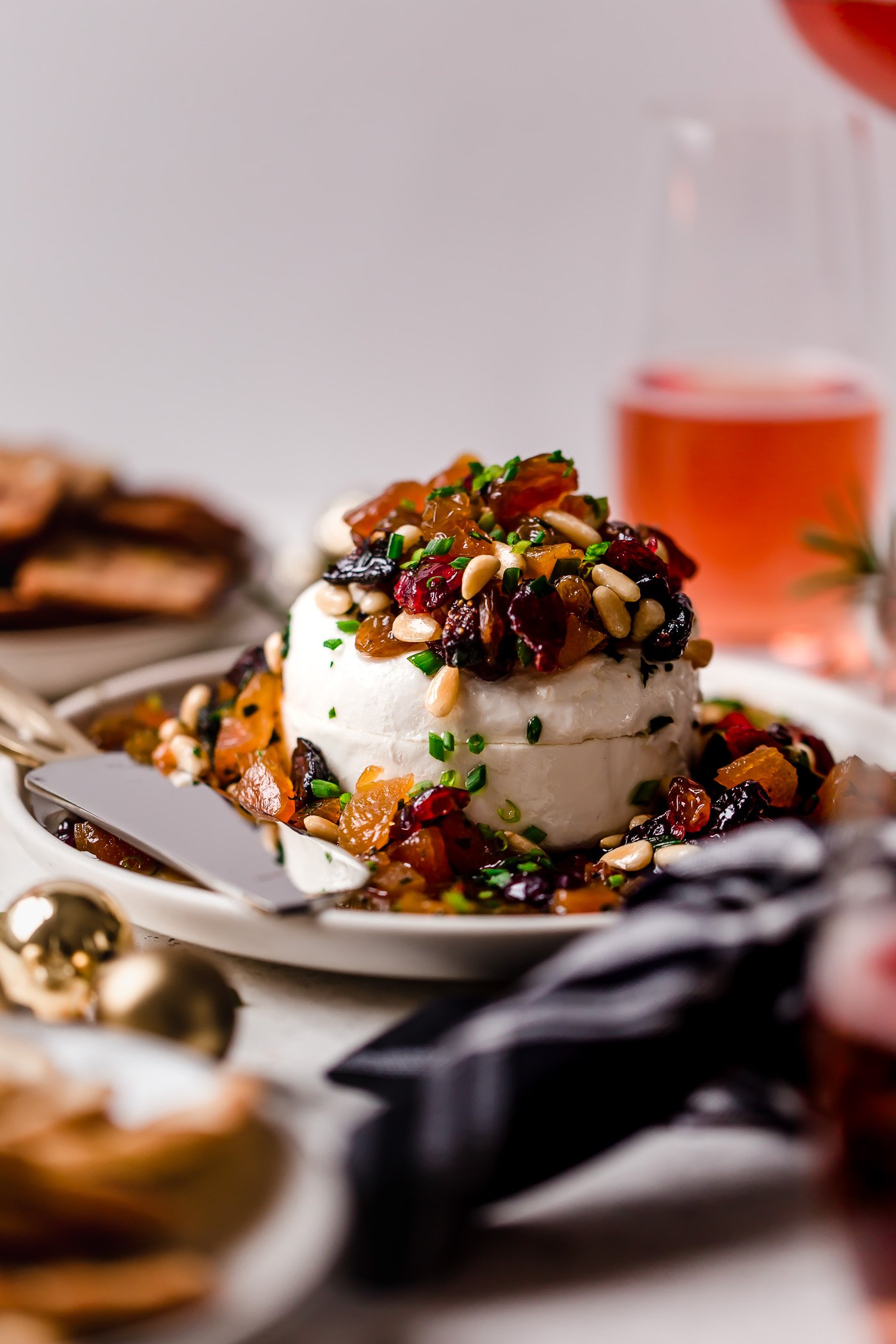 bejeweled holiday marinated goat cheese. easy & beautiful appetizer for any holiday party, this bejeweled holiday marinated goat cheese is always a total show stopper. dried fruits (apricots, golden raisins, figs, cranberries) marinated with fresh herbs & pine nuts, then served over a generous portion of goat cheese. this marinated goat cheese recipe only takes 10 minutes to prep & is always a hit! #playswellwithbutter #marinatedgoatcheese #cheeseball #holidayappetizers #crowdpleaserappetizer