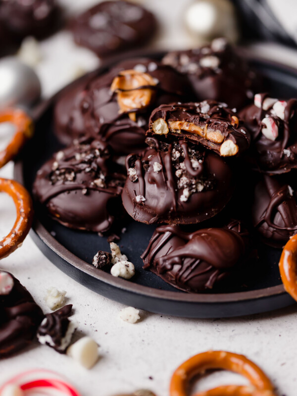 stuffed dark chocolate dipped pretzels. holiday pretzel rounds get filled with peanut butter, salted caramel, oreos, peppermint candies, or any other fillings you love, & covered in dark chocolate. these stuffed dark chocolate dipped pretzels take chocolate covered pretzels to the next level, & they’re the perfect easy no-bake treat to add to your christmas cookie plates this year! #playswellwithbutter #chocolatepretzels #nobakedessert #chocolatedippedpretzels #stuffedpretzels #howtomakechocolatepretzels