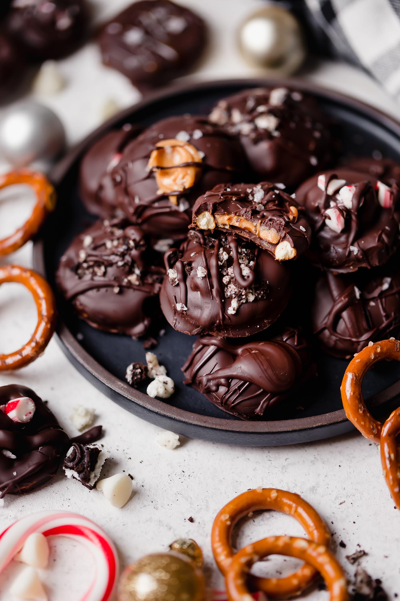 stuffed dark chocolate dipped pretzels. holiday pretzel rounds get filled with peanut butter, salted caramel, oreos, peppermint candies, or any other fillings you love, & covered in dark chocolate. these stuffed dark chocolate dipped pretzels take chocolate covered pretzels to the next level, & they’re the perfect easy no-bake treat to add to your christmas cookie plates this year! #playswellwithbutter #chocolatepretzels #nobakedessert #chocolatedippedpretzels #stuffedpretzels #howtomakechocolatepretzels