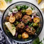 the easiest juicy & tender baked lamb meatballs, made with panko breadcrumbs, lemon, parsley, oregano & cumin, served on top of a seriously healthy meal prep bowl with lemony Greek roasted potatoes, greens, feta, olives, & homemade Romesco sauce. an easy & satisfying meal prep recipe for lunches all week long! #playswellwithbutter #lambmeatballs #bakedlambmeatballs #greeklambmeatballs #groundlamb #mealpreprecipes #mealpreprecipesfortheweek #mediterraneandiet #healthybowlsrecipe