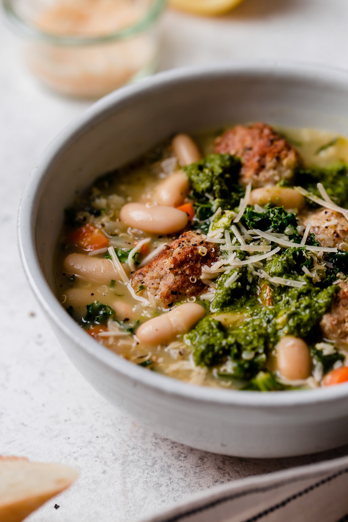 a healthy italian wedding soup recipe, made with tender chicken meatballs, quinoa, kale & cannellini beans. this lightened-up italian wedding soup gets an extra punch of flavor from lemon juice & lots of pesto, making it a cozy & comforting soup & fresh easy weeknight dinner all at once! #playswellwithbutter #italianweddingsoup #italianweddingsouprecipe #easyitalianweddingsoup #chickenmeatballsoup #chickenmeatballs #souprecipes #comfortfood #comfortfooddinners #soup #italianrecipes #italiansoup
