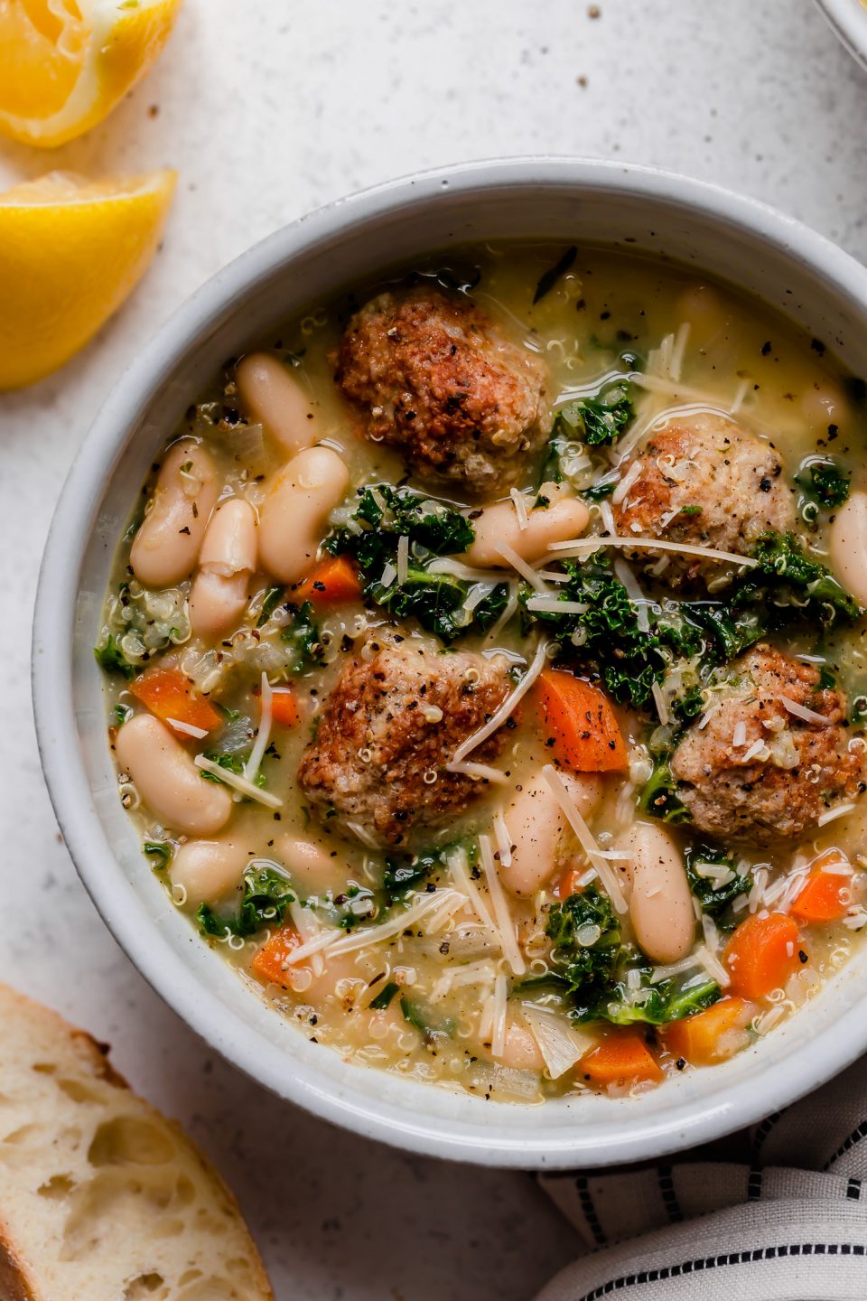 a healthy italian wedding soup recipe, made with tender chicken meatballs, quinoa, kale & cannellini beans. this lightened-up italian wedding soup gets an extra punch of flavor from lemon juice & lots of pesto, making it a cozy & comforting soup & fresh easy weeknight dinner all at once! #playswellwithbutter #italianweddingsoup #italianweddingsouprecipe #easyitalianweddingsoup #chickenmeatballsoup #chickenmeatballs #souprecipes #comfortfood #comfortfooddinners #soup #italianrecipes #italiansoup