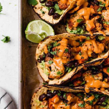 an easy vegetarian tacos recipe filled with easy roasted cauliflower, roasted sweet potatoes, black beans, topped with vegan chipotle lime cashew crema. these roasted sweet potato + cauliflower tacos are totally weeknight-friendly, made in 40 minutes or less, making this the perfect vegetarian taco recipe for taco tuesday! #tacos #cauliflowertacos #sweetpotatotacos #blackbeantacos #vegetariantacos #vegantacos #healthytacosrecipe #easytacosrecipe #easyvegetarianrecipe #easyveganrecipe #dairyfree