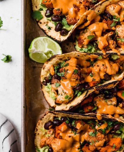 an easy vegetarian tacos recipe filled with easy roasted cauliflower, roasted sweet potatoes, black beans, topped with vegan chipotle lime cashew crema. these roasted sweet potato + cauliflower tacos are totally weeknight-friendly, made in 40 minutes or less, making this the perfect vegetarian taco recipe for taco tuesday! #tacos #cauliflowertacos #sweetpotatotacos #blackbeantacos #vegetariantacos #vegantacos #healthytacosrecipe #easytacosrecipe #easyvegetarianrecipe #easyveganrecipe #dairyfree