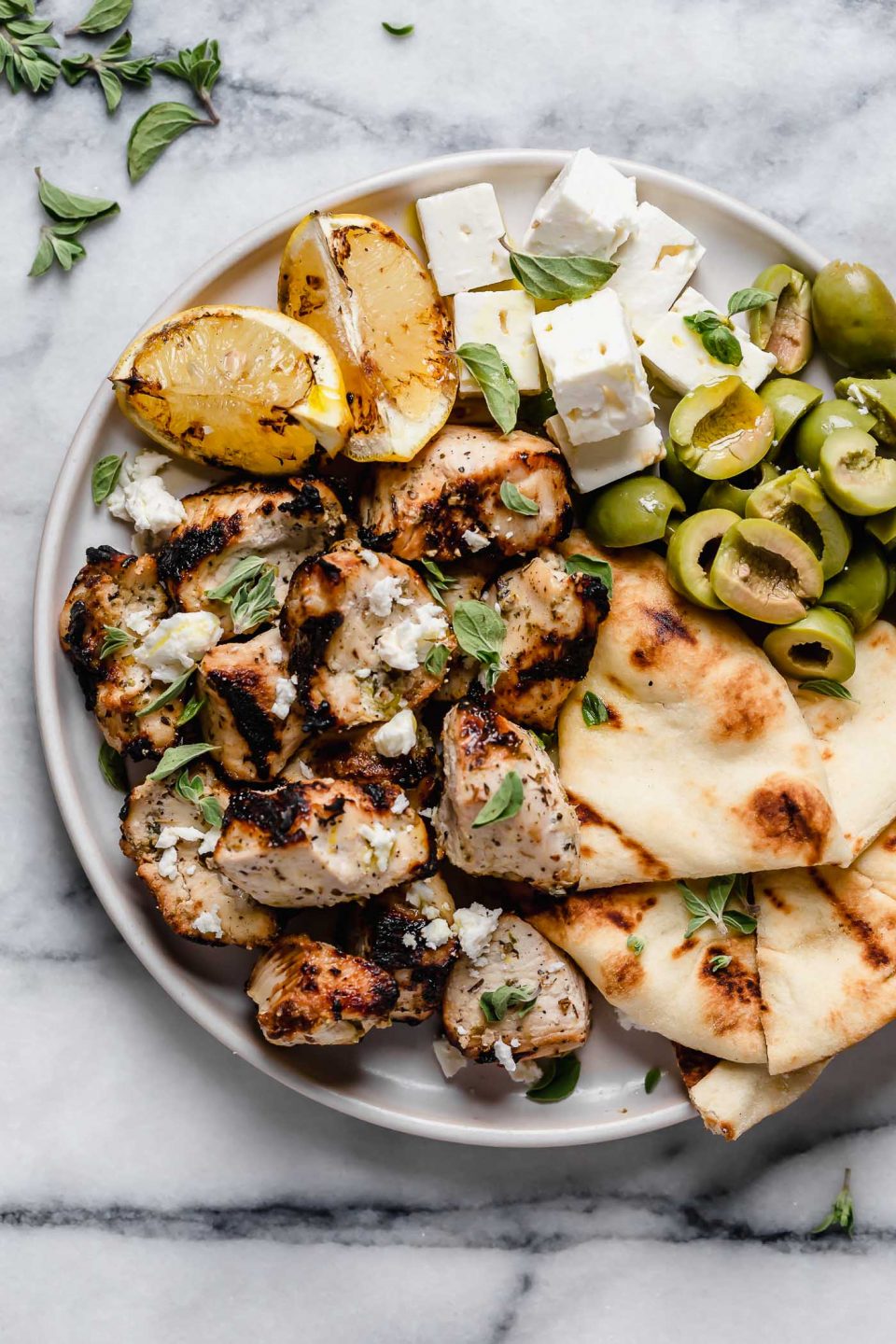 Diced grilled Greek chicken served on a mezze plate with grilled lemon, pita, olives, and cubed feta cheese.