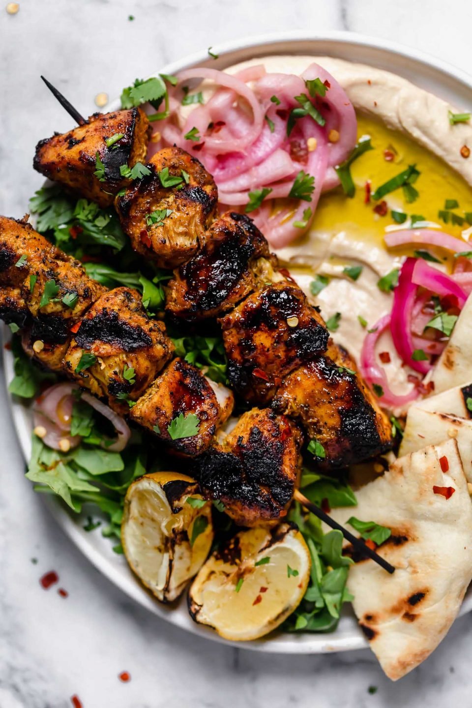 Grilled chicken shawarma served over hummus with pita, pickled onions, & grilled lemons.
