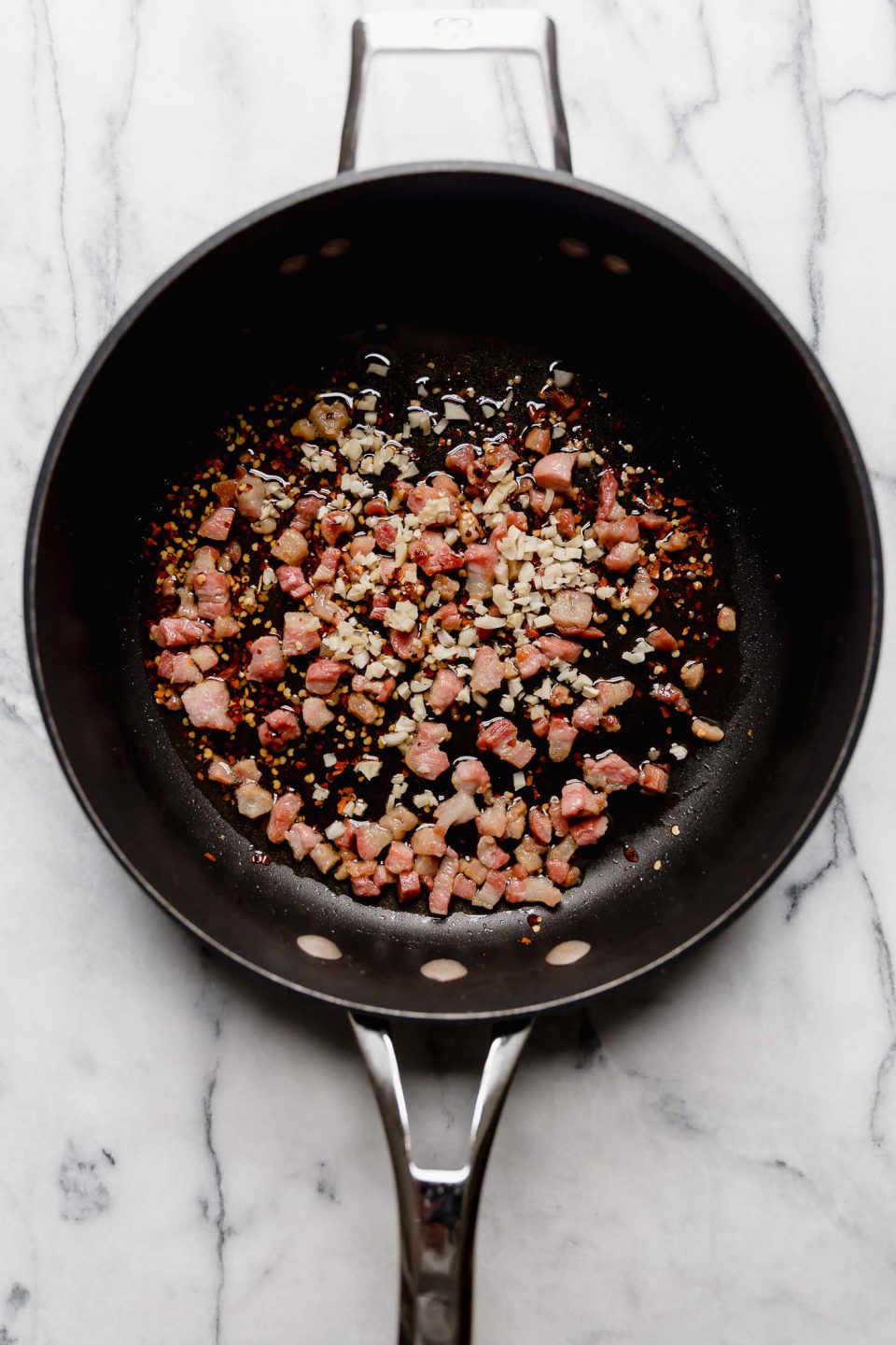 How to make Amatriciana sauce, Step 1: Pancetta, garlic, and red chili flakes in a skillet.