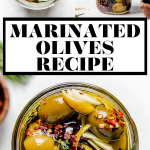 Homemade marinated olives served in a white dish with scalloped edges. The bowl is atop a copper wire rack on a white surface, surrounded by fresh rosemary, lemon peel, a small wooden bowl with red chili flakes, & a couple glasses of red wine.