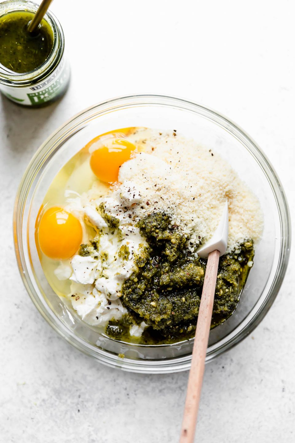 Pesto, Ricotta, Eggs & Parmesan cheese in a mixing bowl.