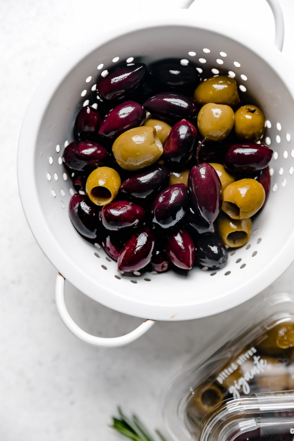 DeLallo calamata olives & gigante olives in a strainer, next to their packaging.