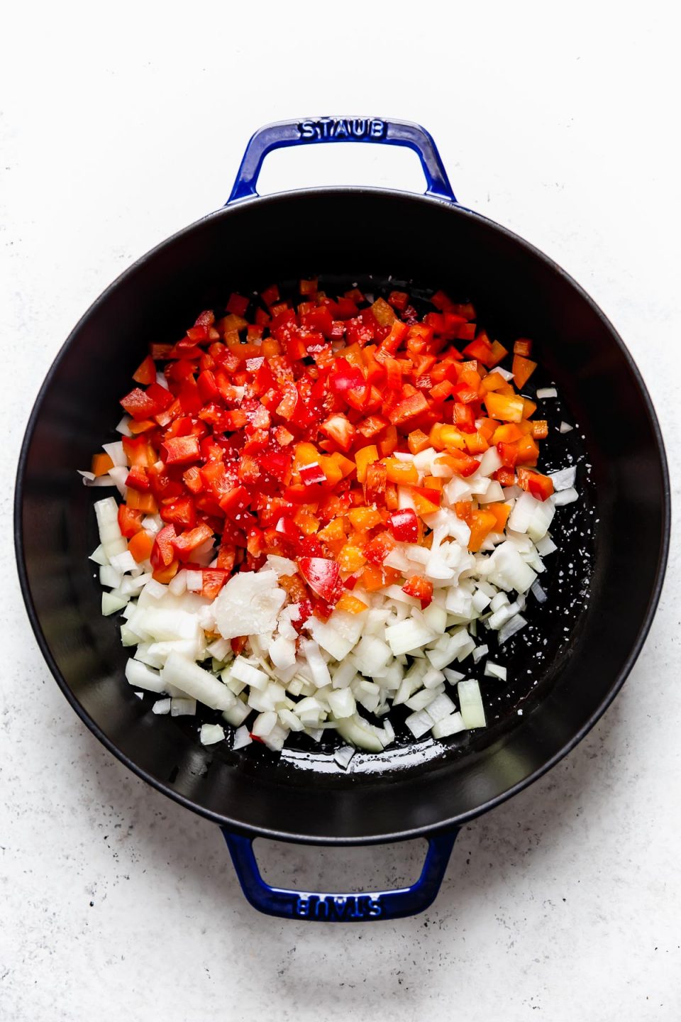 How to make Healthy Stuffed Peppers filling: sweating bell peppers & onions in a large blue skillet.