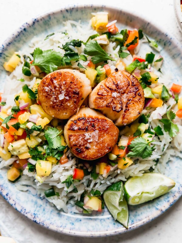 3 seared scallops served on a blue plate with coconut rice & mango salsa. The easiest healthy seared scallops recipe!