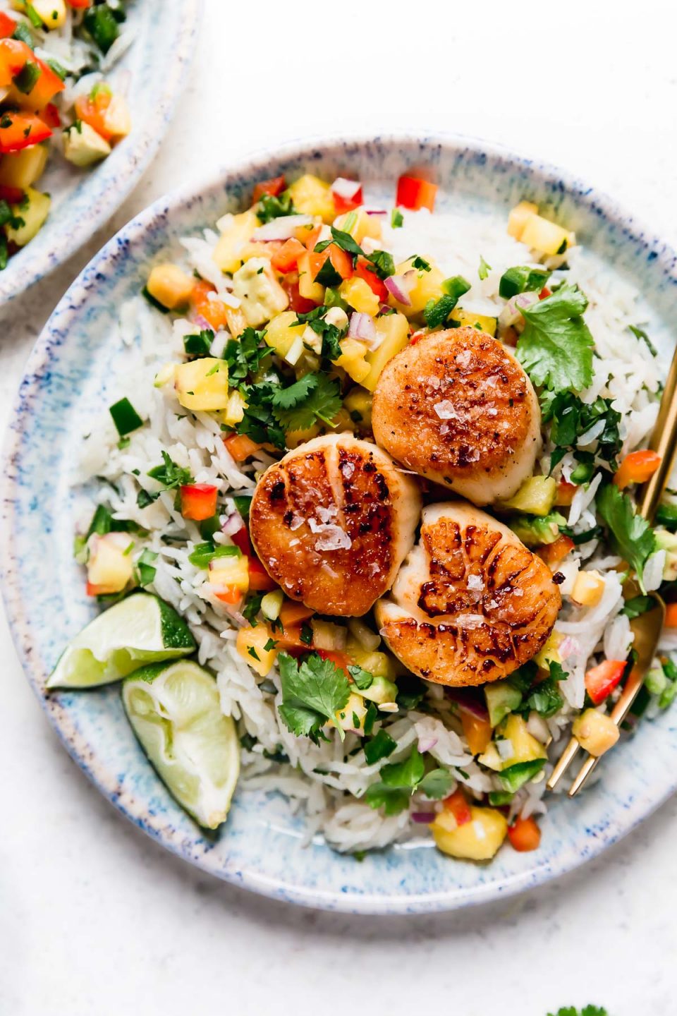 3 seared scallops served on a blue plate with coconut rice & mango salsa. The easiest healthy seared scallops recipe!