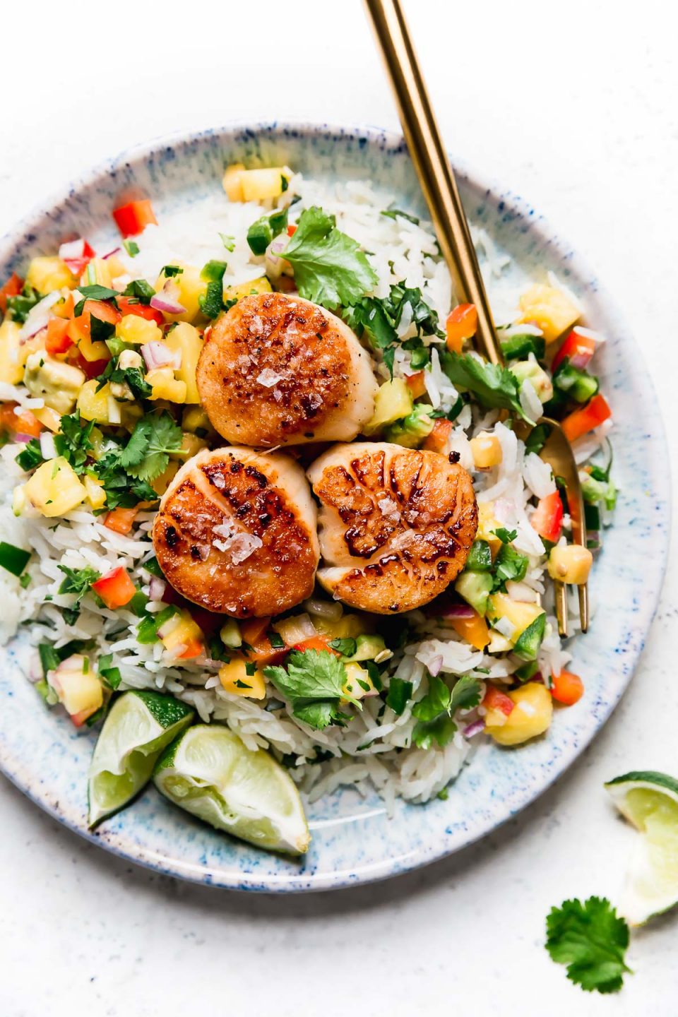 3 seared scallops served on a blue plate with coconut rice & mango salsa. The easiest healthy seared scallops recipe!