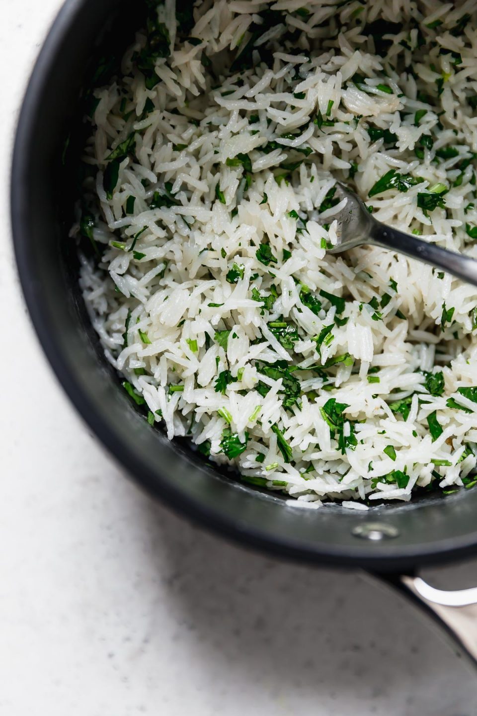 Coconut rice, in a pot, with cilantro and lime zest. The perfect easy side dish to serve with Seared Scallops & Mango Salsa!