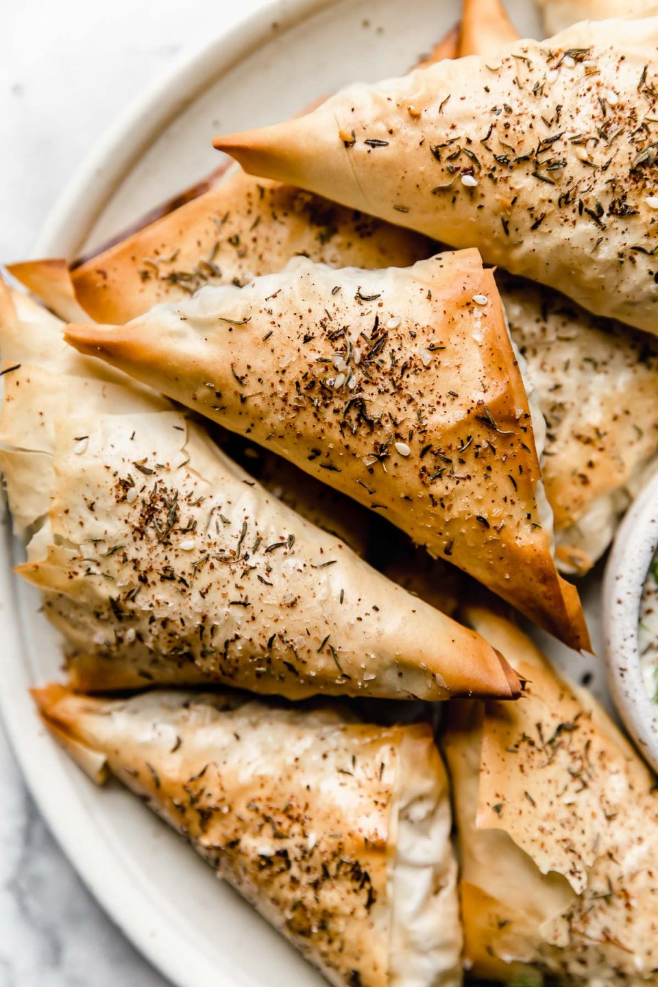 Baked Spanakopita triangles on a ceramic plate.