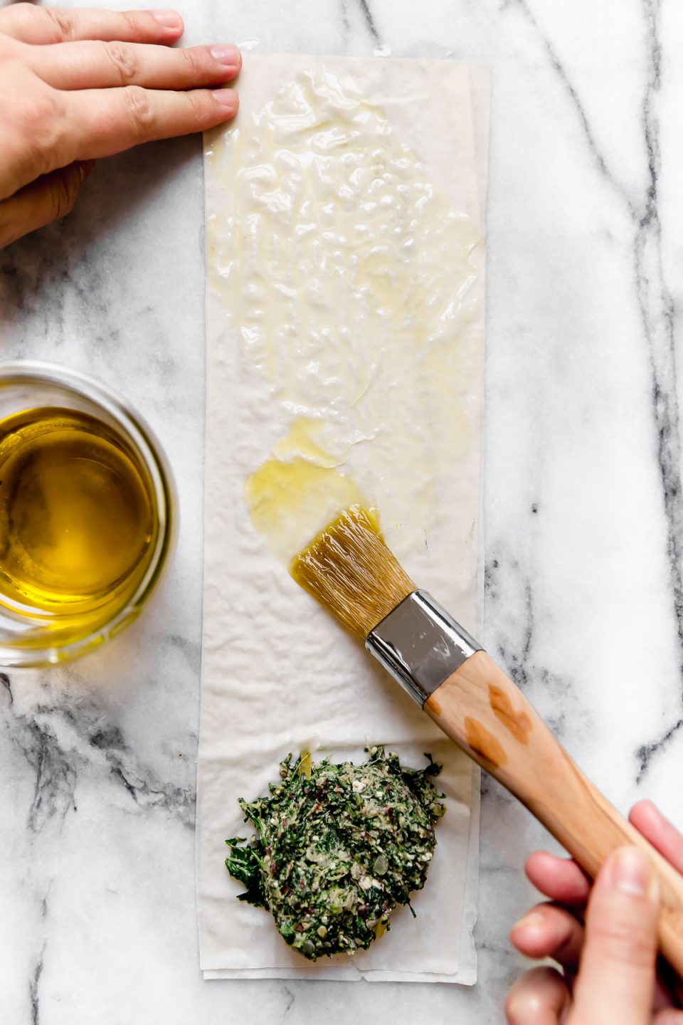 Brushing olive oil over the phyllo dough.