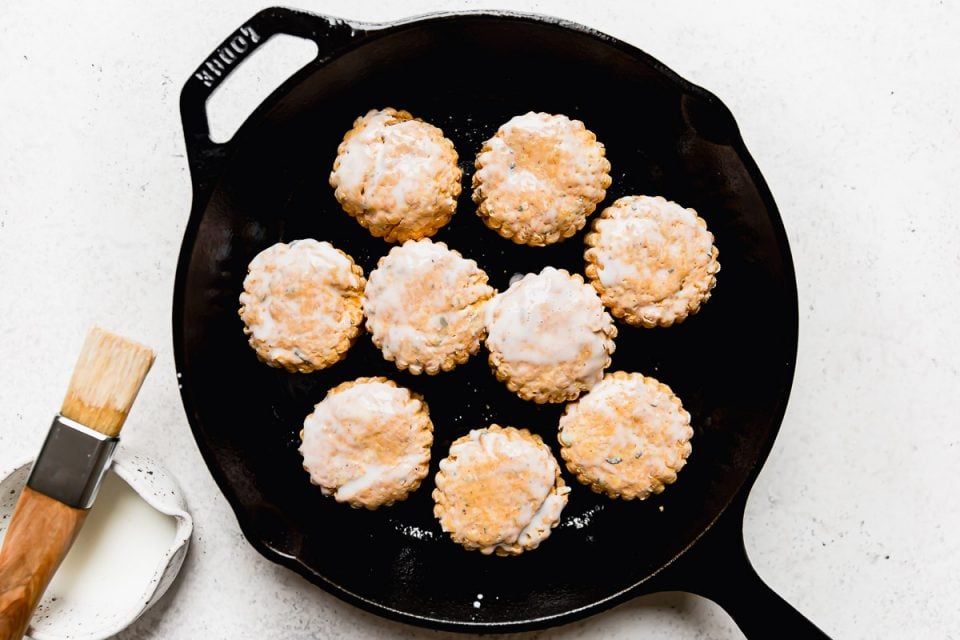 Pumpkin biscuits arranged in a Lodge cast iron skillet, topped with a brushing of buttermilk.