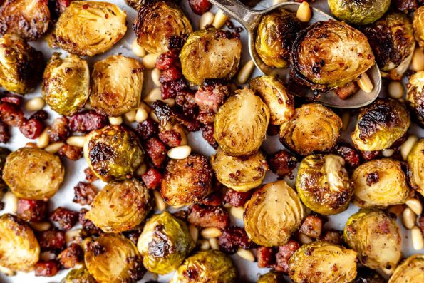 Close view of maple mustard roasted brussels sprouts with pancetta & pine nuts on a large baking sheet.