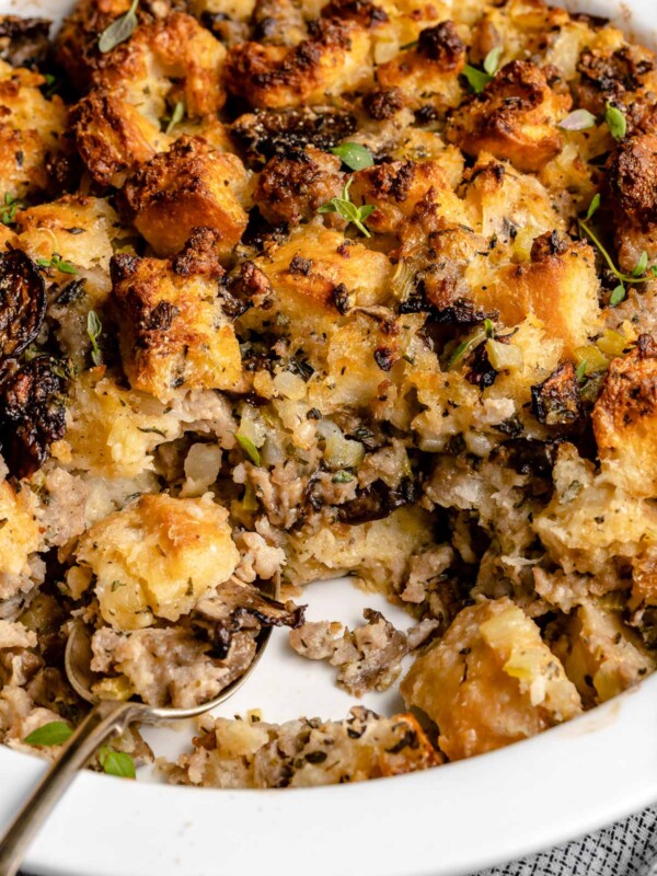 Side angle of sourdough sausage stuffing in baking dish with spoonful taken out, showing the creamy center.