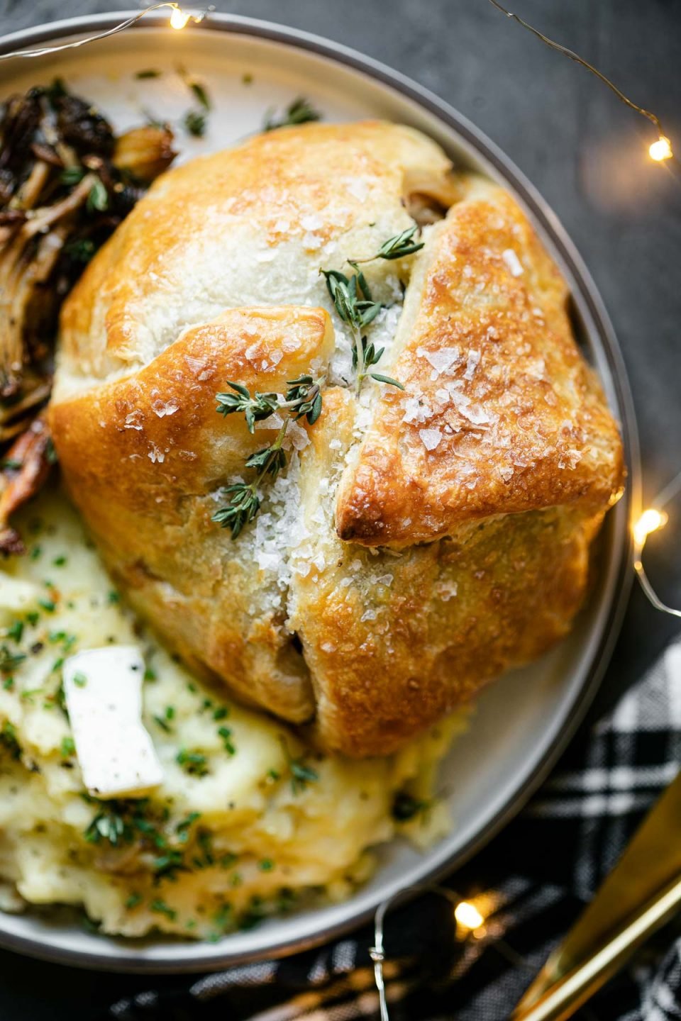 Overhead close up of baked Beef Wellington, topped with fresh herbs and flaky sea salt.