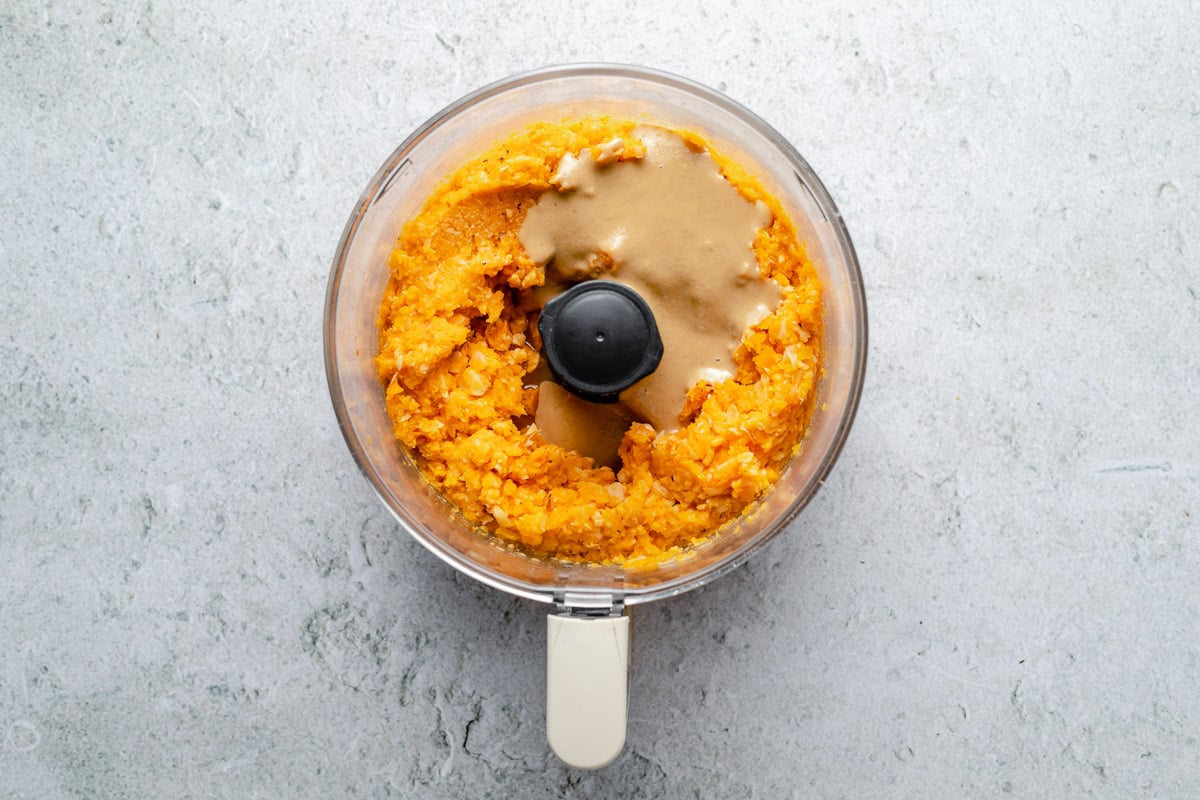 Overhead image of pureed roasted butternut squash and tahini in a food processor bowl without a lid.