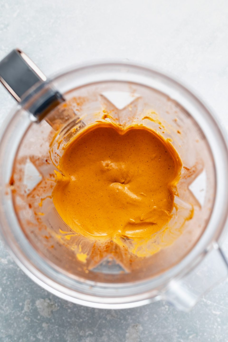 An overhead shot of blended Smoky Chipotle Cashew Crema inside of an open high-speed blender carafe.