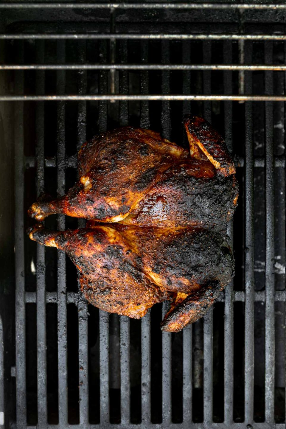 Blackened spatchcocked/butterflied chicken on grill grates.