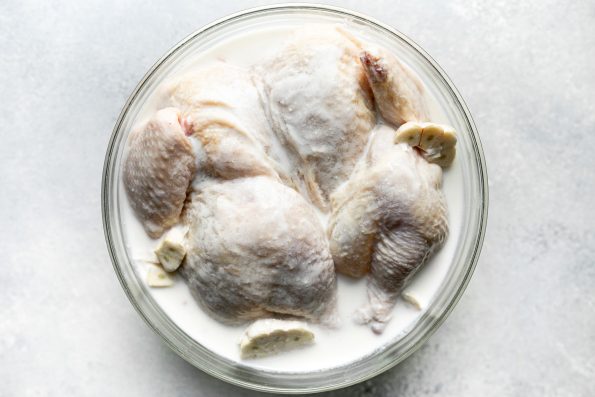 How to grill whole chicken, Step 1: Spatchcocked whole chicken in buttermilk brine with whole garlic.
